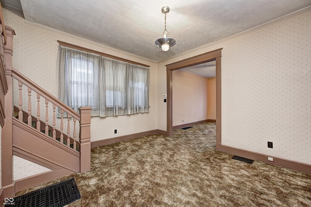 carpeted foyer entrance with a textured ceiling and ornamental molding