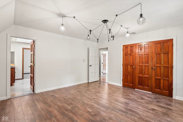 unfurnished bedroom featuring lofted ceiling, ensuite bathroom, and dark hardwood / wood-style floors