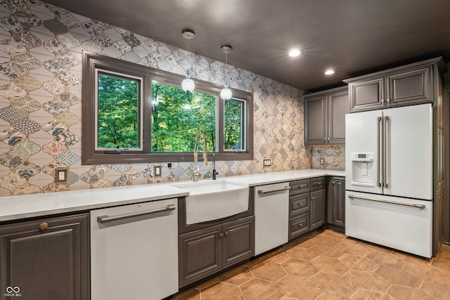 kitchen with high end fridge, hanging light fixtures, sink, and stainless steel dishwasher