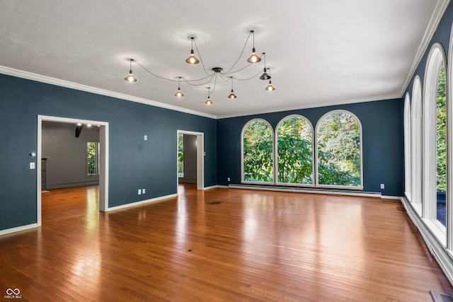 empty room featuring hardwood / wood-style flooring, crown molding, and a notable chandelier