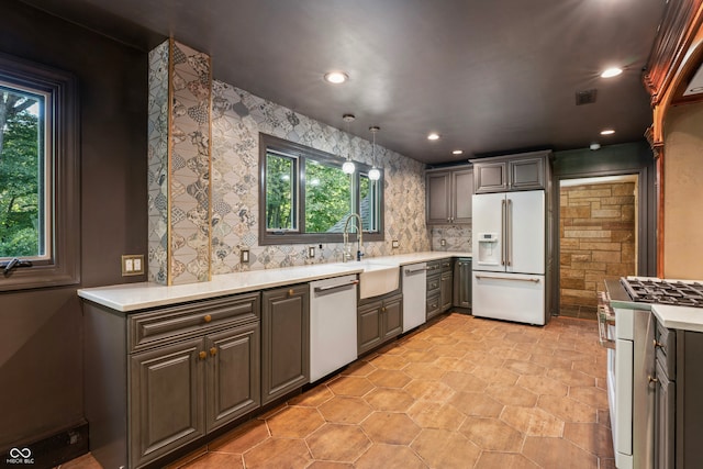 kitchen featuring pendant lighting, white appliances, decorative backsplash, and sink