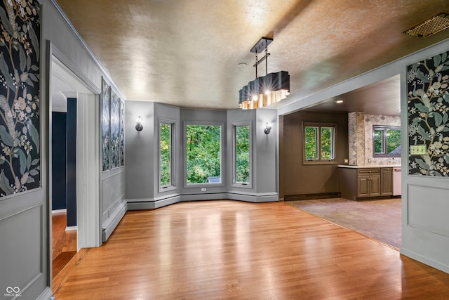 unfurnished dining area featuring a chandelier and light hardwood / wood-style floors