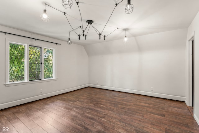 spare room featuring lofted ceiling and dark hardwood / wood-style flooring