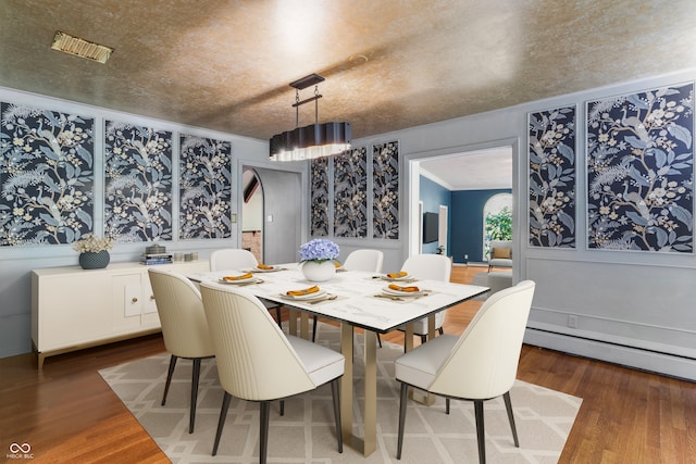 dining space featuring a baseboard radiator, crown molding, and dark wood-type flooring