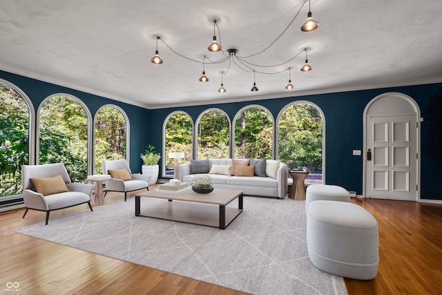 living room featuring light wood-type flooring, ornamental molding, and a healthy amount of sunlight