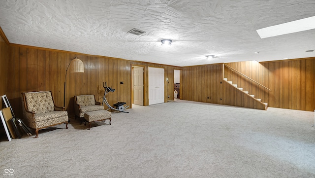 unfurnished room featuring wood walls, carpet, and a textured ceiling