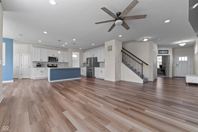 unfurnished living room featuring sink, ceiling fan, and light hardwood / wood-style flooring