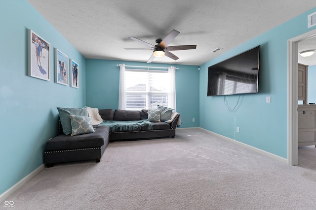 carpeted living room featuring ceiling fan and a textured ceiling