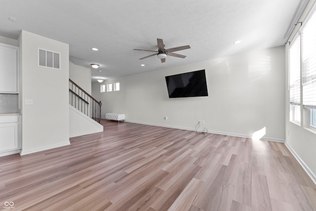 unfurnished living room with ceiling fan, a textured ceiling, and light wood-type flooring