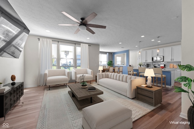 living room featuring a textured ceiling, light wood-type flooring, and ceiling fan