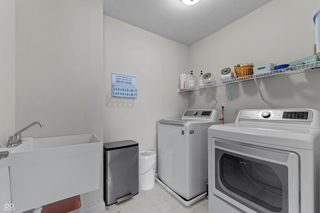 laundry room with independent washer and dryer, a textured ceiling, and sink