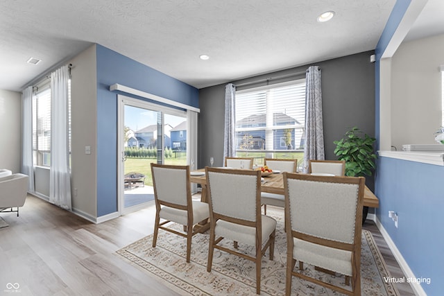 dining space with light hardwood / wood-style flooring, a textured ceiling, and plenty of natural light