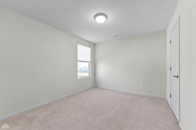 unfurnished room with a textured ceiling and light colored carpet