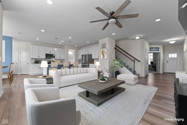 living room with light hardwood / wood-style flooring and ceiling fan