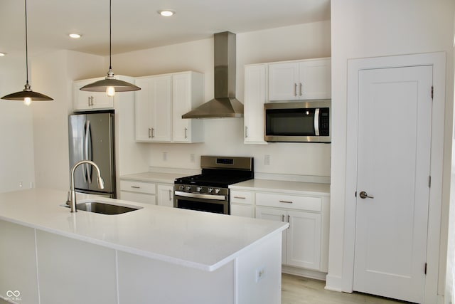 kitchen with appliances with stainless steel finishes, pendant lighting, wall chimney range hood, and white cabinetry