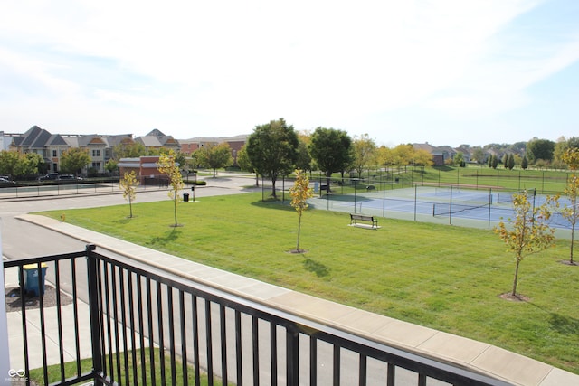 view of property's community featuring tennis court and a lawn