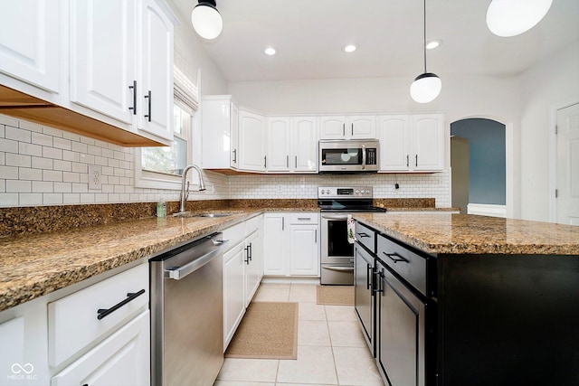 kitchen featuring stainless steel appliances, sink, stone counters, white cabinets, and a kitchen island