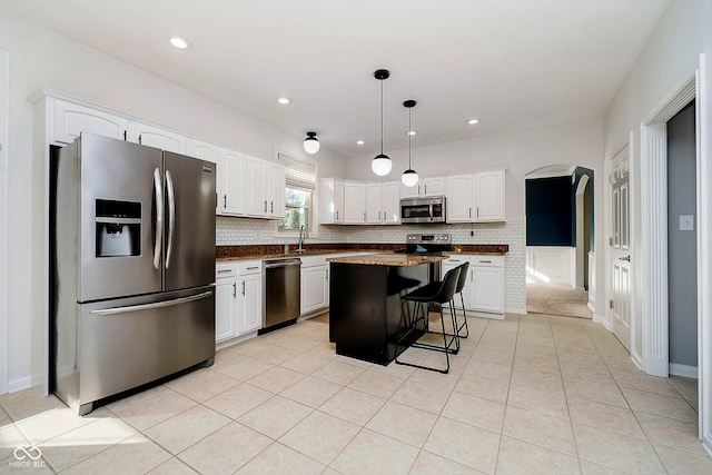 kitchen featuring a center island, stainless steel appliances, pendant lighting, a breakfast bar, and white cabinets