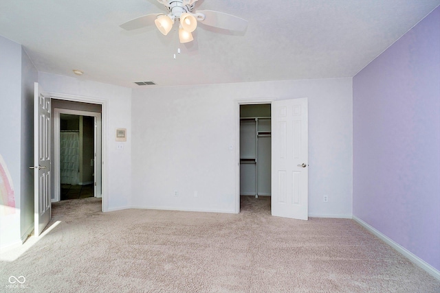 unfurnished bedroom with ceiling fan, a closet, light colored carpet, and a spacious closet