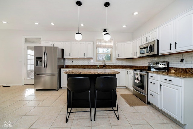 kitchen featuring sink, light tile patterned floors, a kitchen island, white cabinetry, and stainless steel appliances