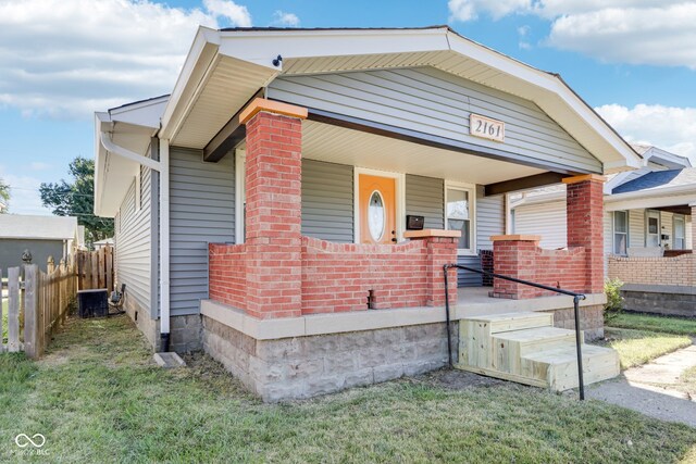 view of front of home featuring a front yard, central AC unit, and a porch