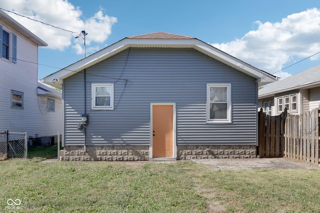 back of property with fence and a lawn