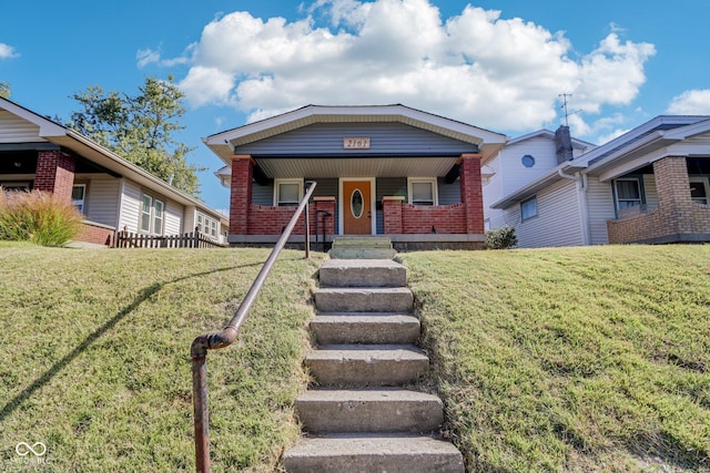bungalow-style home with covered porch, a front lawn, and brick siding