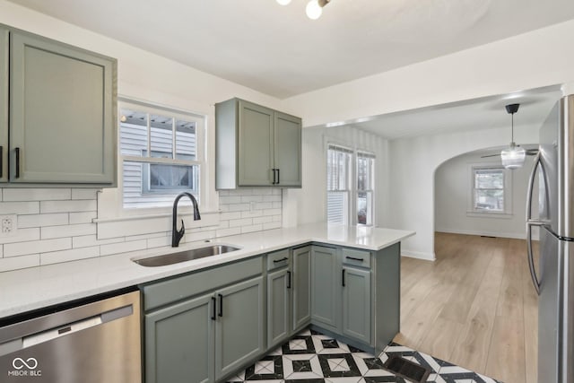 kitchen with pendant lighting, appliances with stainless steel finishes, tasteful backsplash, sink, and kitchen peninsula