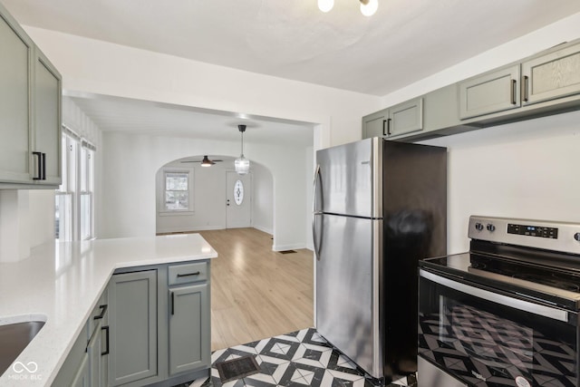 kitchen featuring ceiling fan, kitchen peninsula, hanging light fixtures, light wood-type flooring, and stainless steel appliances