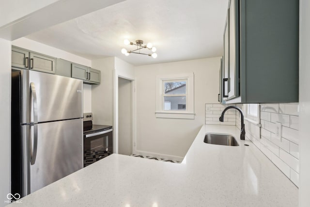 kitchen with appliances with stainless steel finishes, tasteful backsplash, an inviting chandelier, sink, and green cabinetry