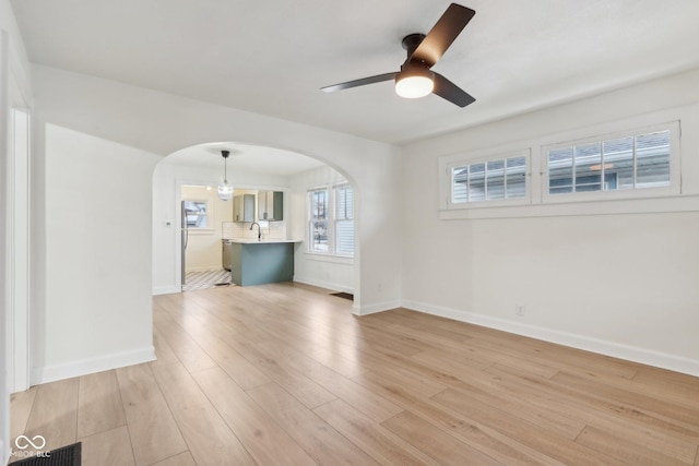 unfurnished room with light hardwood / wood-style floors, sink, and ceiling fan