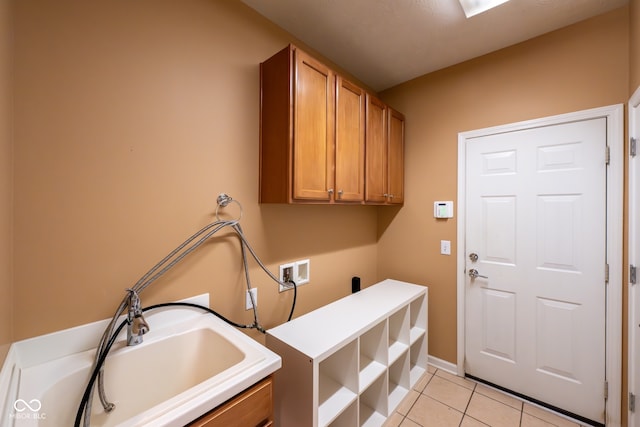 clothes washing area featuring washer hookup, cabinets, light tile patterned floors, and sink