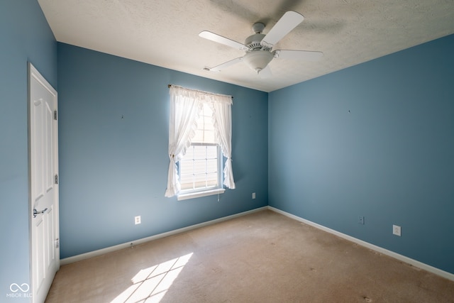 spare room with ceiling fan, light colored carpet, and a textured ceiling