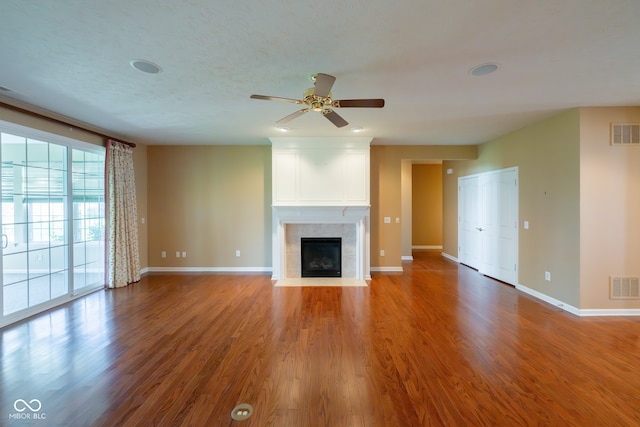 unfurnished living room featuring hardwood / wood-style floors, a textured ceiling, ceiling fan, and a tiled fireplace