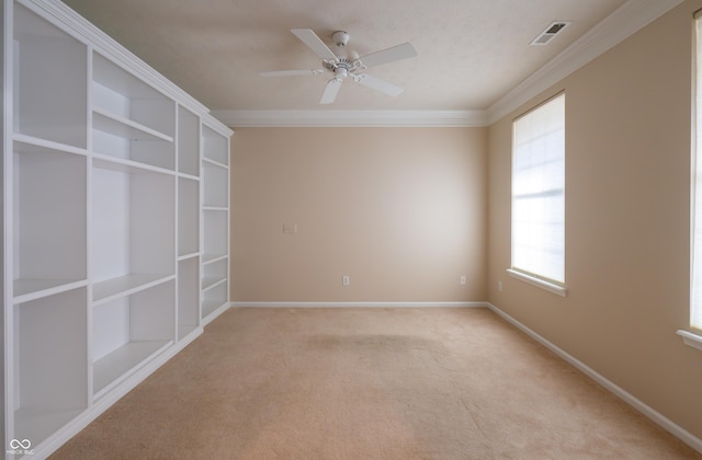 carpeted empty room featuring a wealth of natural light, crown molding, and ceiling fan