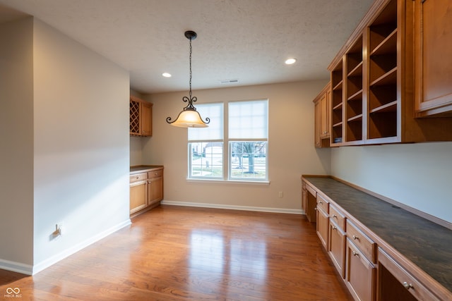 kitchen featuring a textured ceiling, decorative light fixtures, and light hardwood / wood-style floors