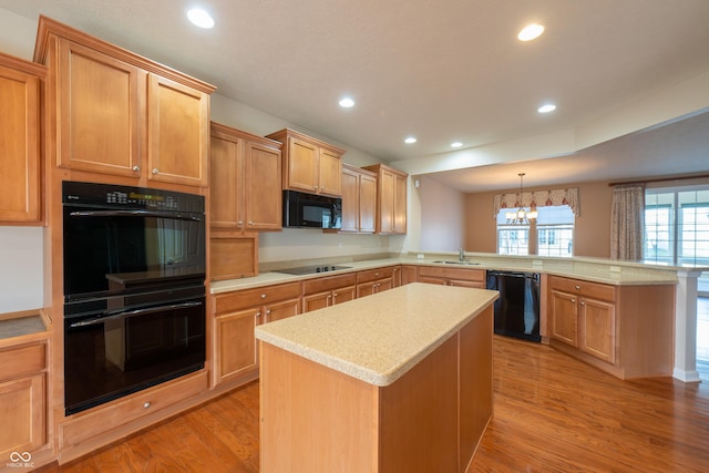 kitchen with pendant lighting, black appliances, sink, a kitchen island, and kitchen peninsula