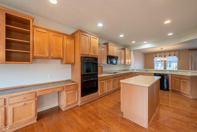 kitchen with kitchen peninsula, black appliances, decorative light fixtures, an inviting chandelier, and light hardwood / wood-style floors