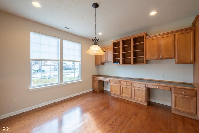 kitchen featuring hardwood / wood-style floors, built in desk, and decorative light fixtures