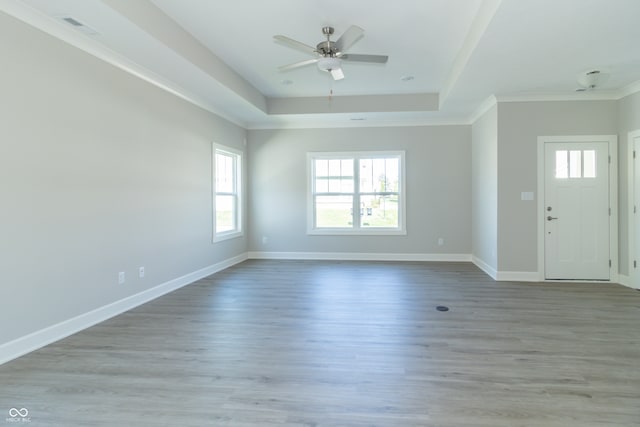 entryway with ceiling fan, light hardwood / wood-style floors, ornamental molding, and a tray ceiling