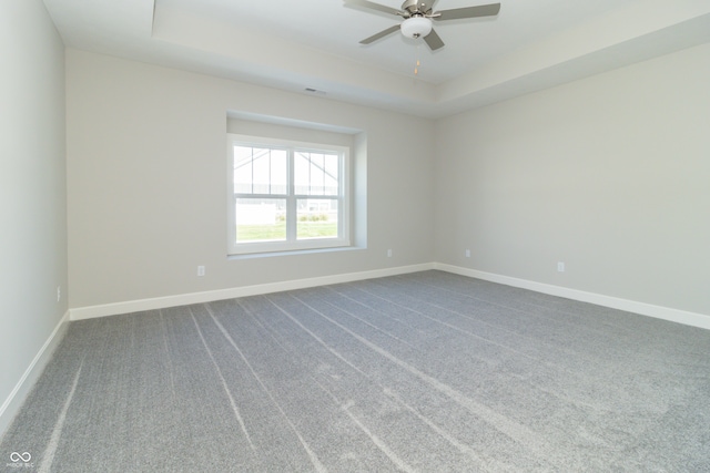 carpeted spare room featuring ceiling fan and a raised ceiling