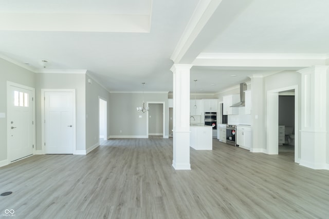 unfurnished living room with ornate columns, sink, an inviting chandelier, light hardwood / wood-style flooring, and crown molding