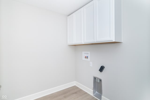 washroom featuring hookup for a washing machine, cabinets, and light hardwood / wood-style flooring