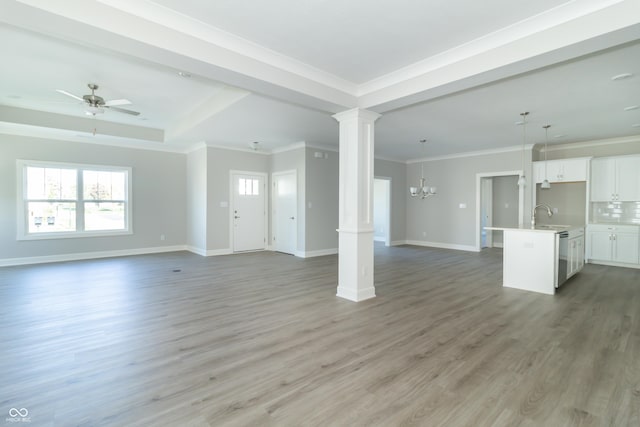 4435 W Preserve Pass, New Palestine, IN 46163 - unfurnished living room featuring a sink, light wood finished floors, baseboards, ornamental molding, and decorative columns