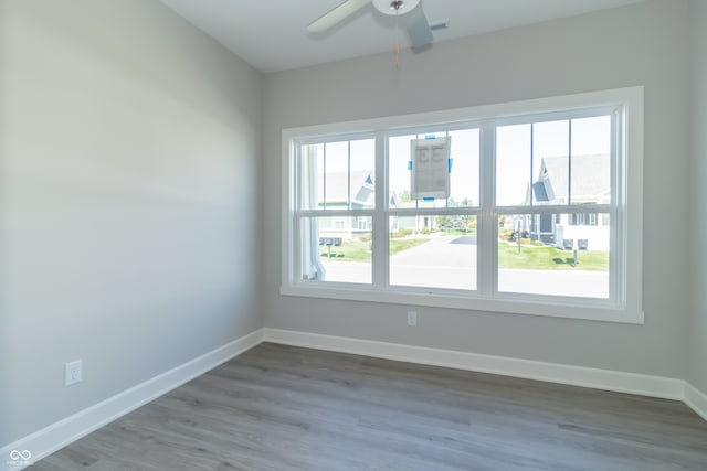 spare room with a healthy amount of sunlight, ceiling fan, and wood-type flooring