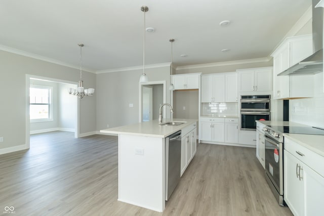 kitchen featuring tasteful backsplash, stainless steel appliances, white cabinets, hanging light fixtures, and an island with sink