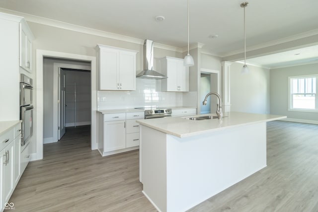 kitchen with white cabinets, decorative light fixtures, wall chimney range hood, and sink