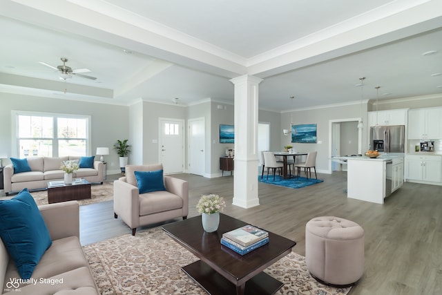 living room with decorative columns, light hardwood / wood-style flooring, ceiling fan, and ornamental molding