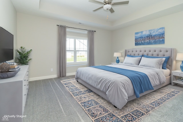 carpeted bedroom with a raised ceiling and ceiling fan