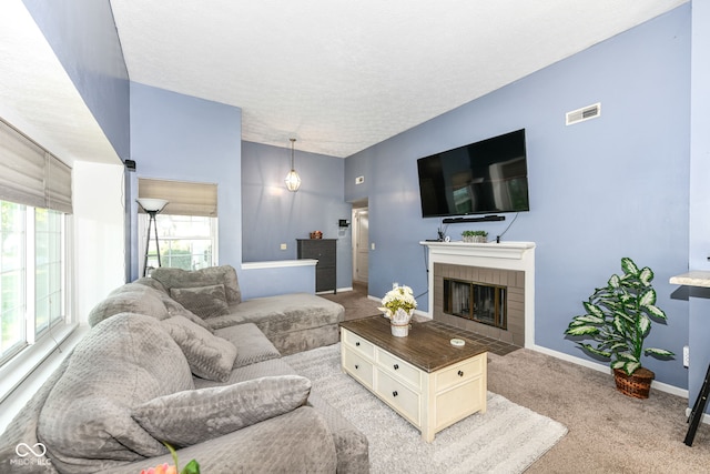 living area featuring light carpet, a brick fireplace, baseboards, visible vents, and a textured ceiling